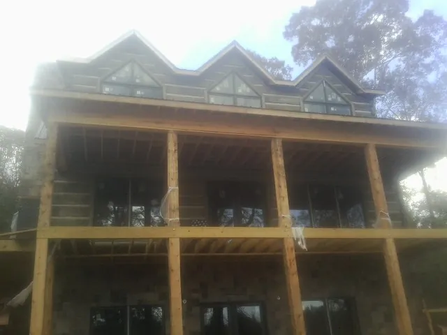 Dormers and porch framing on a large log home under construction — Roof Coating work by our crew in Claremont